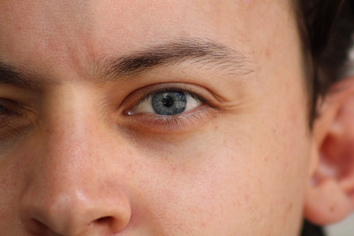 Closeup of process of threading procedure in barber shop. Professional barber correcting shape of brows with threads to smiling young man sitting in chair. Concept of eyebrows care. stock photo