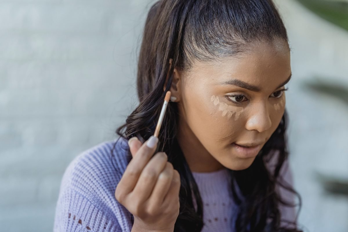Blending concealer under the eye with a damp makeup sponge
